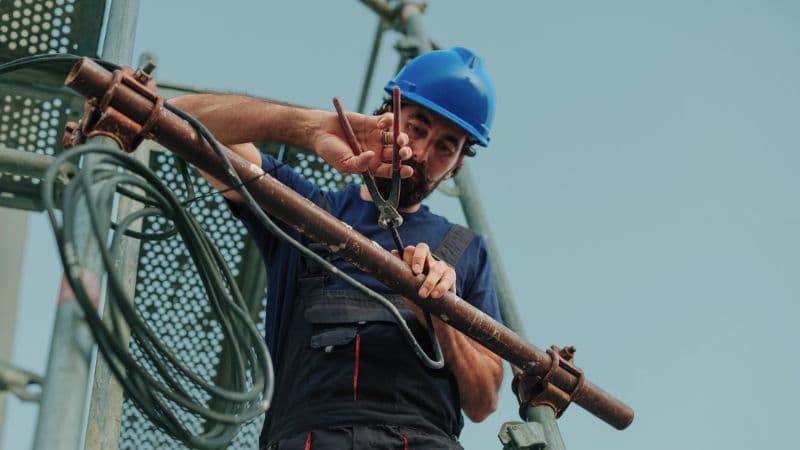 Construction Worker Cutting Wires On Scaffolding Using Pliers